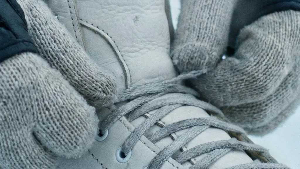 Gros plan sur des mains gantées laçant fermement un patin à glace, avec des protège-poignets visibles, sur fond de glace extérieure