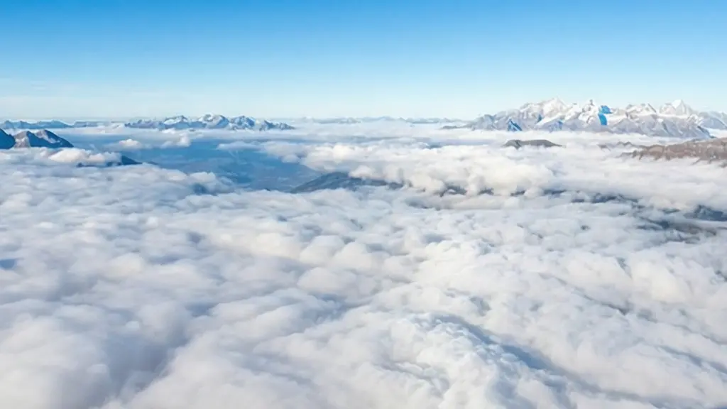 Vue depuis le sommet du Salève au-dessus d'une mer de brouillard dense, avec les Alpes émergeant au loin sous un ciel bleu.