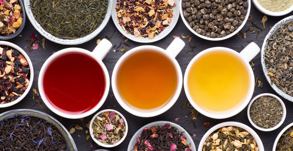 Palette de peintre avec pigments naturels aux nuances chaudes (ocres, verts, ambrés) symbolisant la diversité aromatique des infusions et créations originales